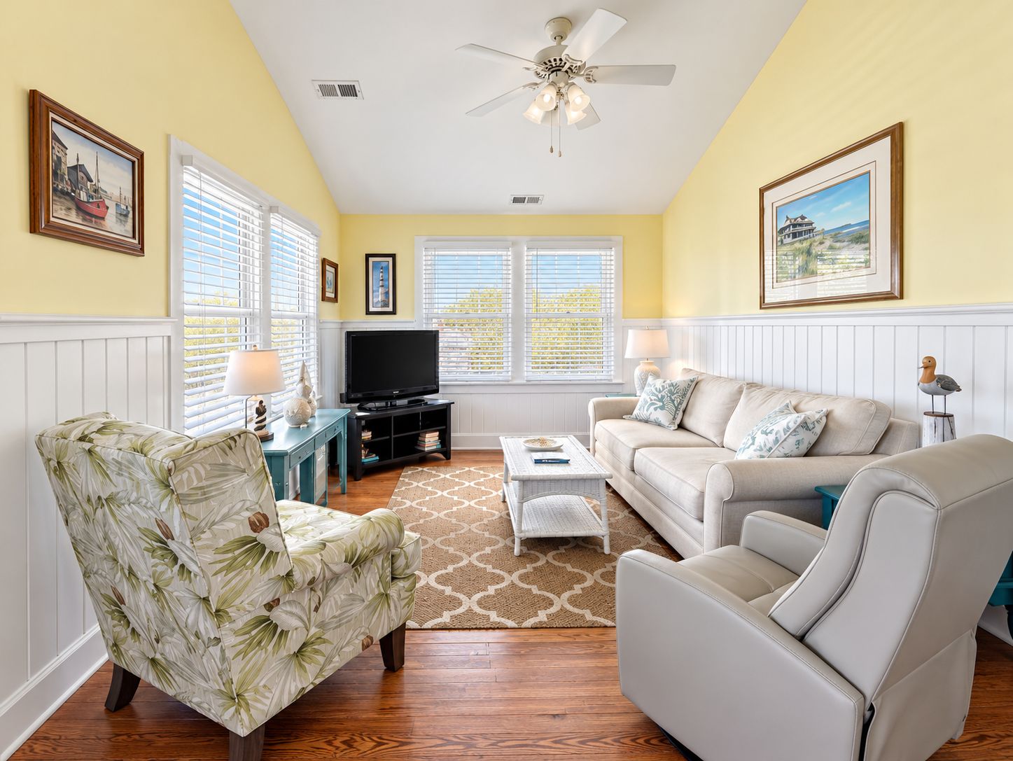 A living room with a television, two sofas, a coffee table, and a patterned armchair.