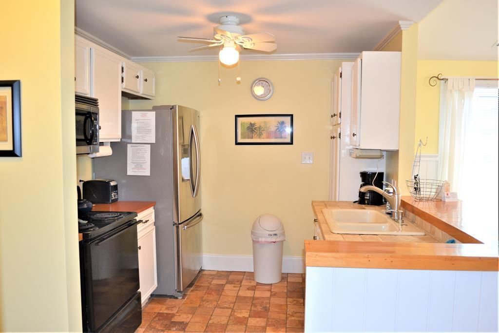A compact kitchen with a stove, microwave, refrigerator, and sink.