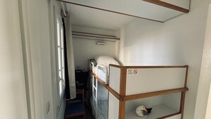 Een kleine kamer met een stapelbed, een bureau en een stoel.
