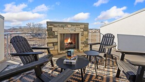 A patio with Adirondack chairs, a stone fireplace, and a view of the city. - Mountain View Home w/ King Beds & Rooftop Deck (Fort Collins)