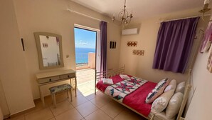 Una camera da letto con un letto, una scrivania, una sedia, uno specchio grande e vista mare.