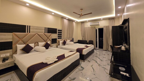 A hotel room with two beds, a ceiling fan, an air conditioning unit, a TV, and a minibar. - Elegant Beach Resort (Kanthi)