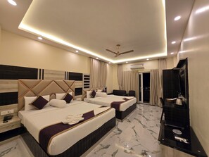 A hotel room with two beds, a ceiling fan, an air conditioning unit, a TV, and a minibar. - Elegant Beach Resort (Kanthi)