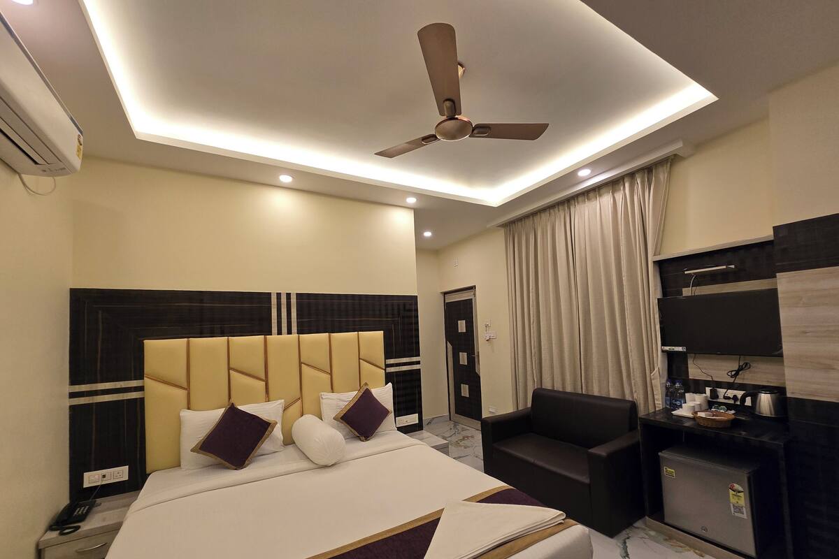 Una habitación de hotel con una cama grande, ventilador de techo, televisor y escritorio con silla.