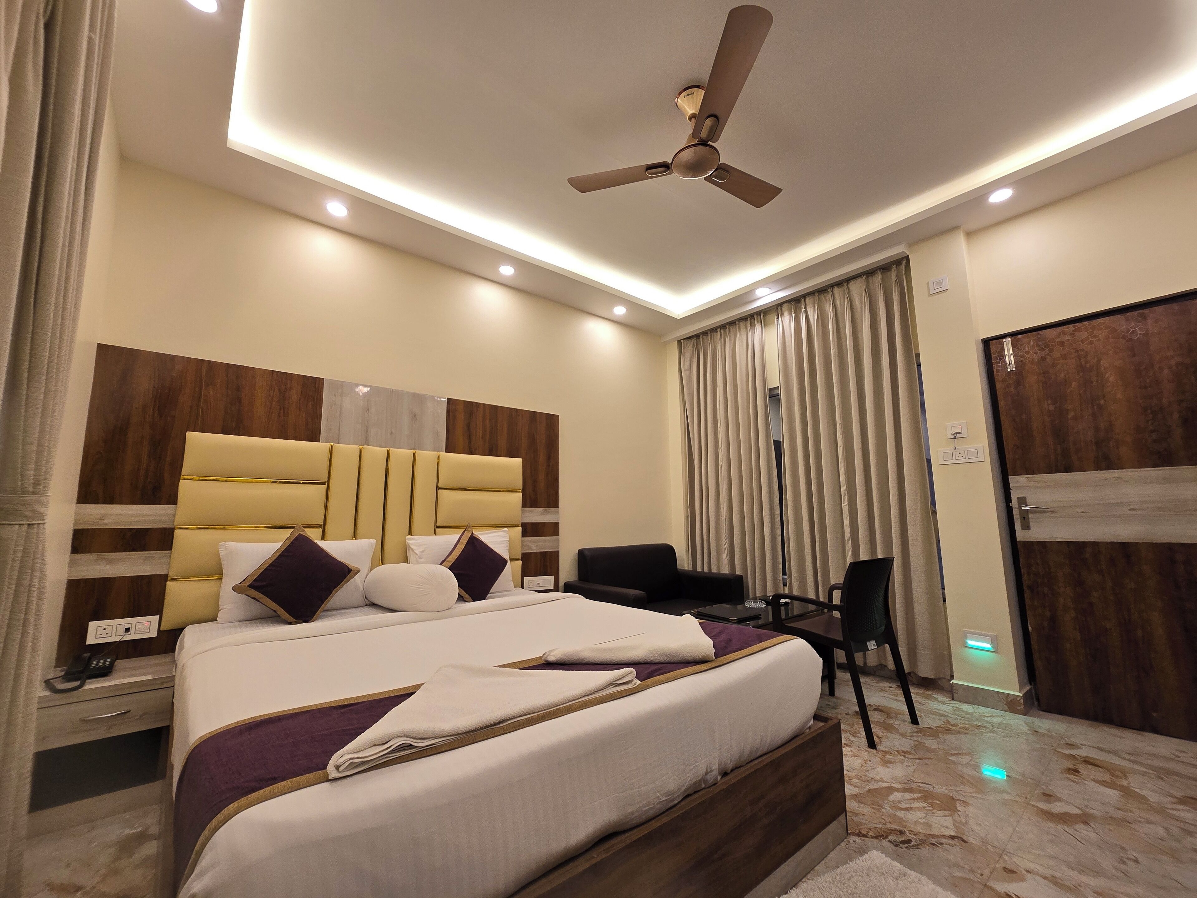 Une chambre moderne avec un grand lit, un ventilateur de plafond et un bureau avec une chaise.