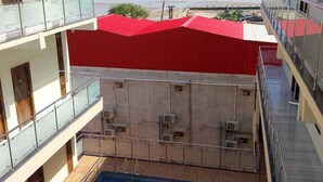 A swimming pool with a red roof, a view of the beach, and a multi-level building with balconies. - Elegant Beach Resort (Kanthi)