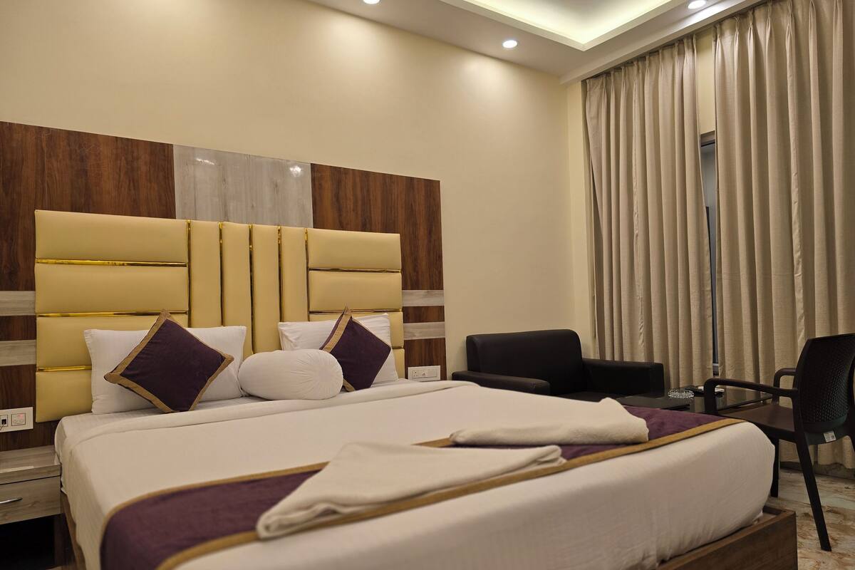 Una habitación de hotel moderna con una cama grande, un cabecero de madera, un escritorio y una silla.