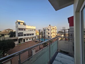 A balcony with a view of a residential area, including buildings and a swimming pool. - Elegant Beach Resort (Kanthi)