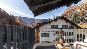 Ein Balkon mit Blick auf Berge und ein Gebäude mit der Aufschrift 'ALPENBLICK'.