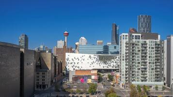 Un quartier urbain moderne qui présente un mélange de bâtiments commerciaux et résidentiels, notamment un bâtiment blanc remarquable avec une façade géométrique et une haute tour surmontée d’une flèche.
