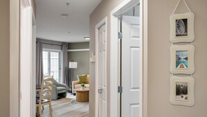 A hallway with a dining area, a sofa, and a lamp. - Spacious Riverfront DT Condo: 3 Beds, AC, Heated Parking, Stampede & Saddledome (Calgary)