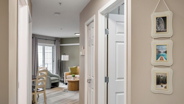 A hallway with a dining area, a sofa, and a lamp. - Modern 3 Beds, A/C, Underground Parking, Saddledome & Stampede (Calgary)