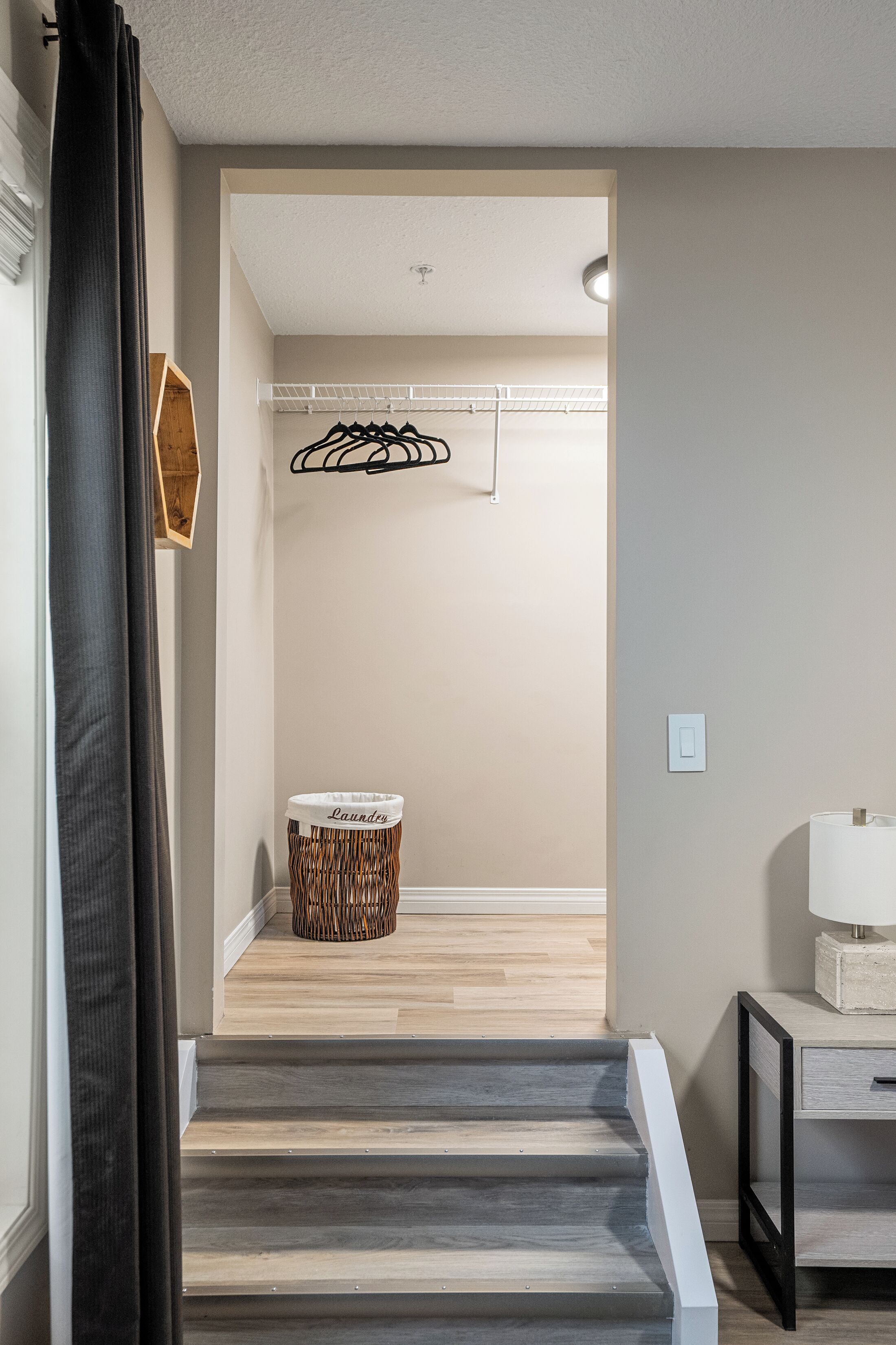 A staircase leading to a laundry area with a hanging rack and a basket labeled "Laundry."