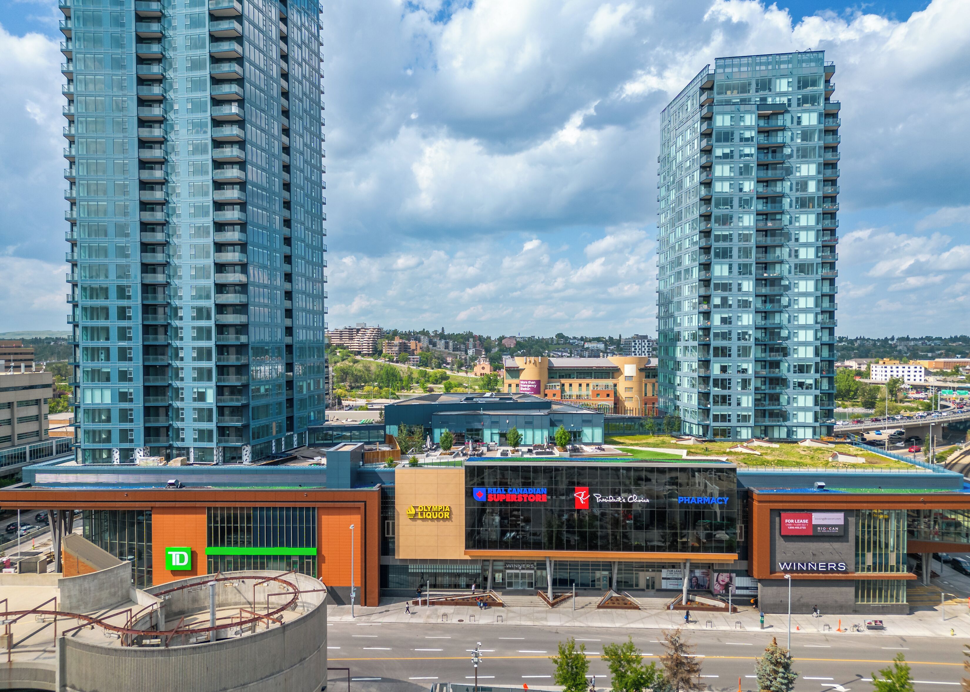 A modern building with a glass facade, a TD sign, and a pharmacy.