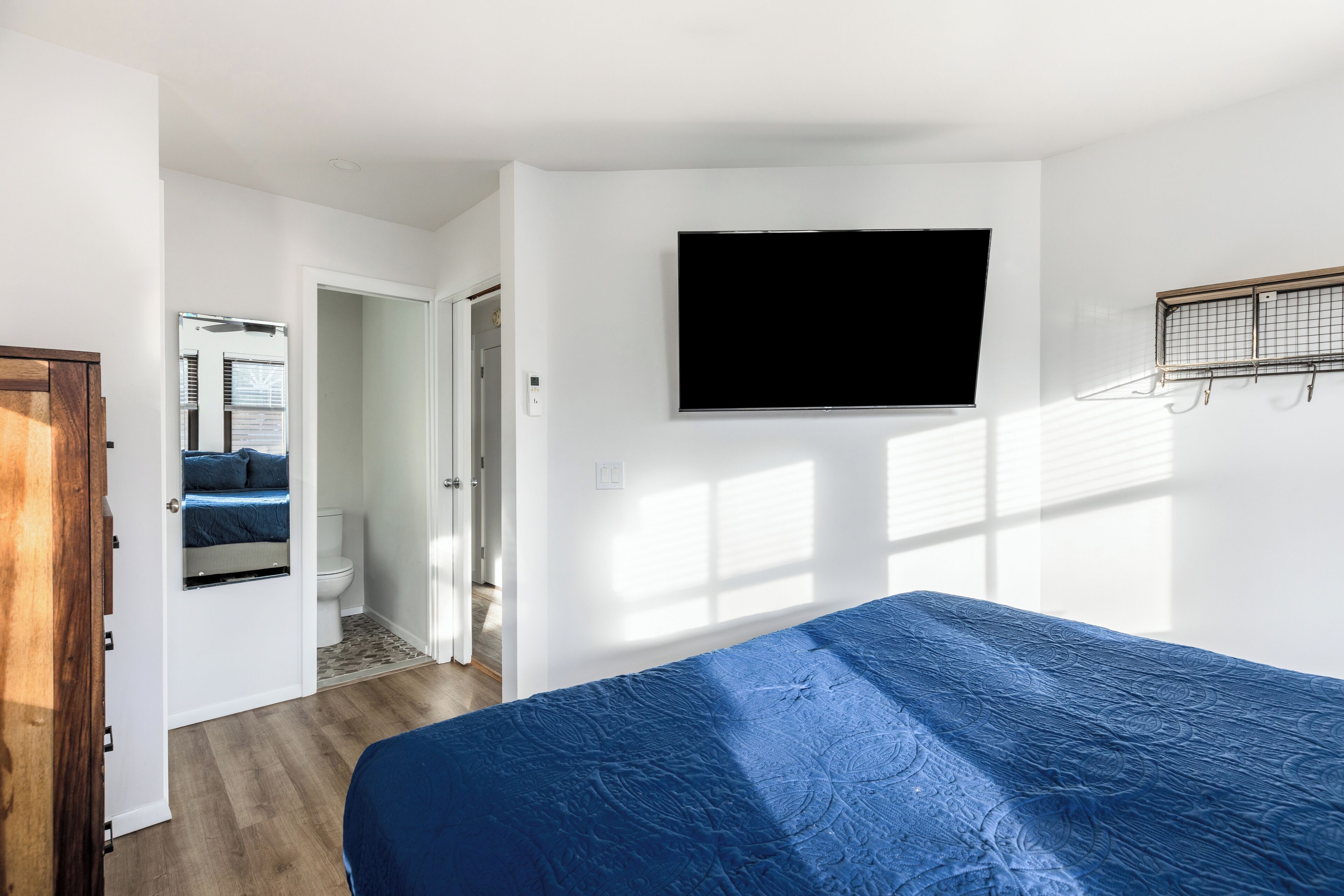 Une chambre à coucher avec un lit, un téléviseur fixé au mur et une fenêtre avec des stores.