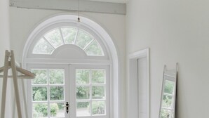 A room with a large arched window, a ladder, and a mirror leaning against the wall.