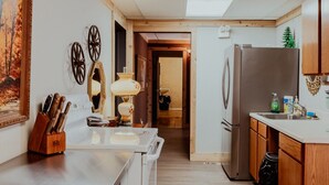 A kitchen with wooden cabinets, a refrigerator, a sink, and a dining area with a table and chairs.