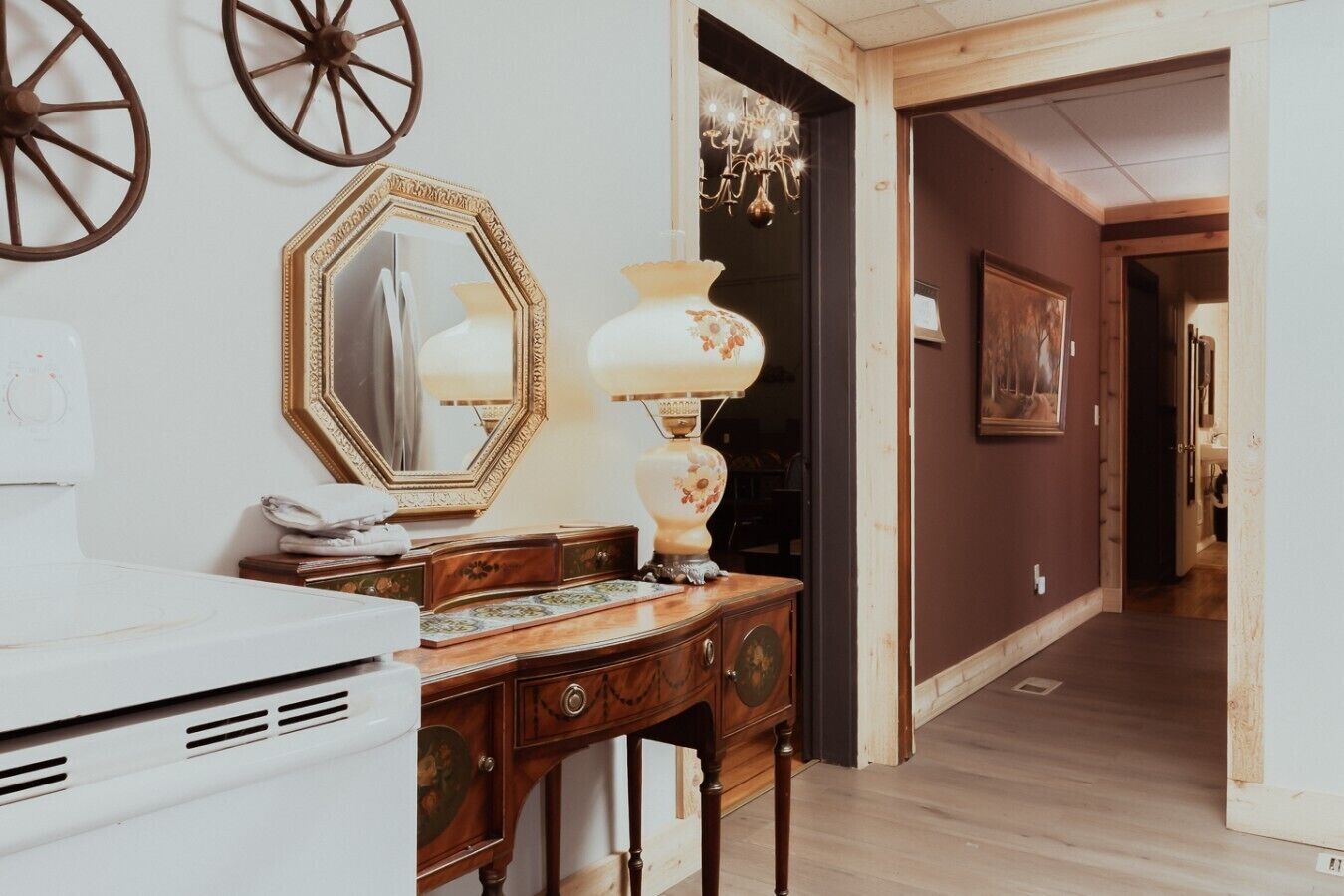 A room with a wooden dresser, a mirror, a lamp, and a chandelier.