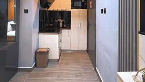 A modern kitchen with a microwave, stove, and cabinets. - DE CALMA APARTMENTS (Abuja)
