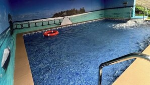 An indoor swimming pool with a lifebuoy, a diving board, and a mural on the wall. - DE CALMA APARTMENTS (Abuja)