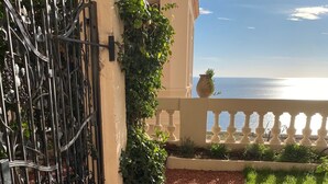 Un chemin recouvert de gravier rouge mène à un balcon d’où l’on peut admirer la mer.