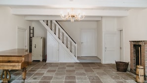 A spacious hallway with a staircase, a chandelier, and a fireplace. - North SeaEstate under thatch with sauna near Sankt Peter-Ording / Eiderstedt peninsula (Tetenbüll)