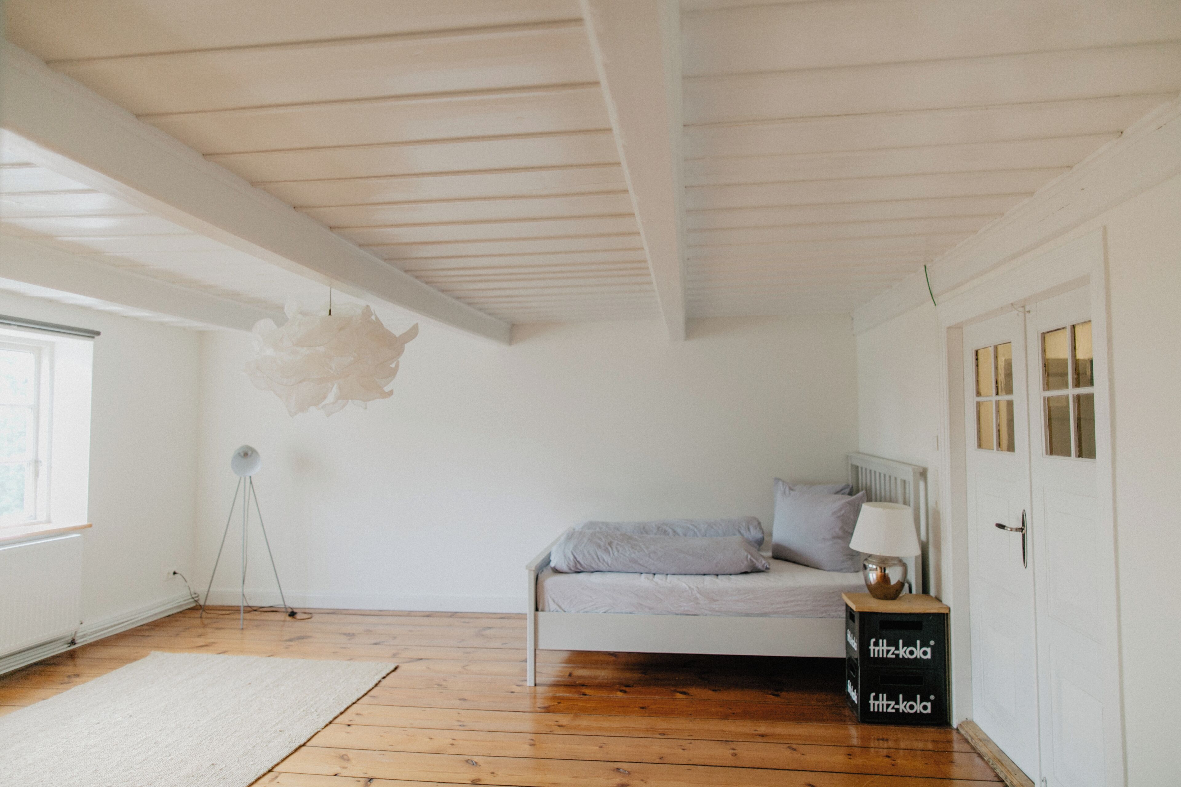 A bedroom with a bed, a lamp, a floor lamp, a radiator, and a white door.