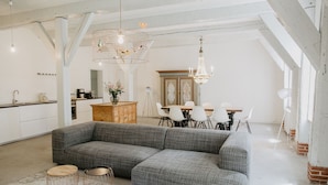 A spacious living area with a large sectional sofa, a dining table with chairs, and a kitchen area. - North SeaEstate under thatch with sauna near Sankt Peter-Ording / Eiderstedt peninsula (Tetenbüll)
