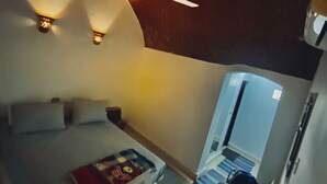 Ein Schlafzimmer mit Bett, Kissen, Nachttisch, einem Buch, Deckenventilator und Fenster.