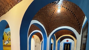 Ein Korridor mit blauen und weißen Wänden, Ziegelbögen und Fliesenböden.