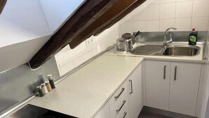 A kitchen with white cabinets, a stainless steel sink, and a black induction cooktop.