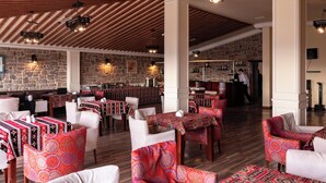A spacious restaurant with high wooden ceilings, patterned carpets, and white upholstered chairs. - SECRET HOTEL (Baku)