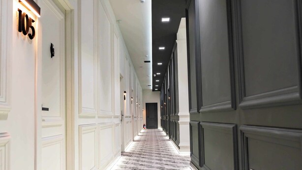 A long, narrow hallway with a checkered floor pattern, white walls, and dark paneling on one side. - SECRET HOTEL (Baku)