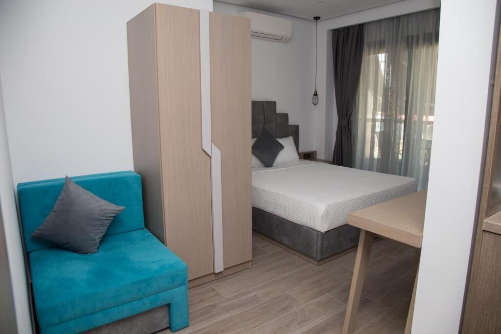 A compact bedroom with a bed, a small table, a sofa, and a wardrobe.