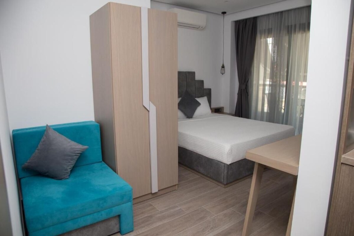Un dormitorio pequeño con cama, una mesita, un sofá y un armario.