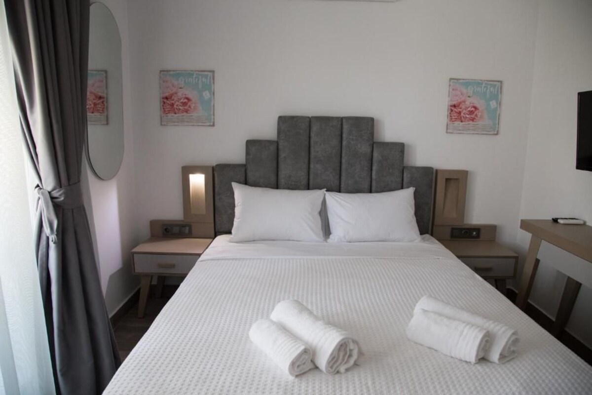 A hotel room with a large bed, two bedside tables, a headboard, and a flat-screen TV.