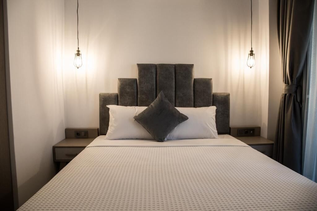 A neatly made bed with a patterned bedspread, two bedside tables, and a headboard with a geometric design.