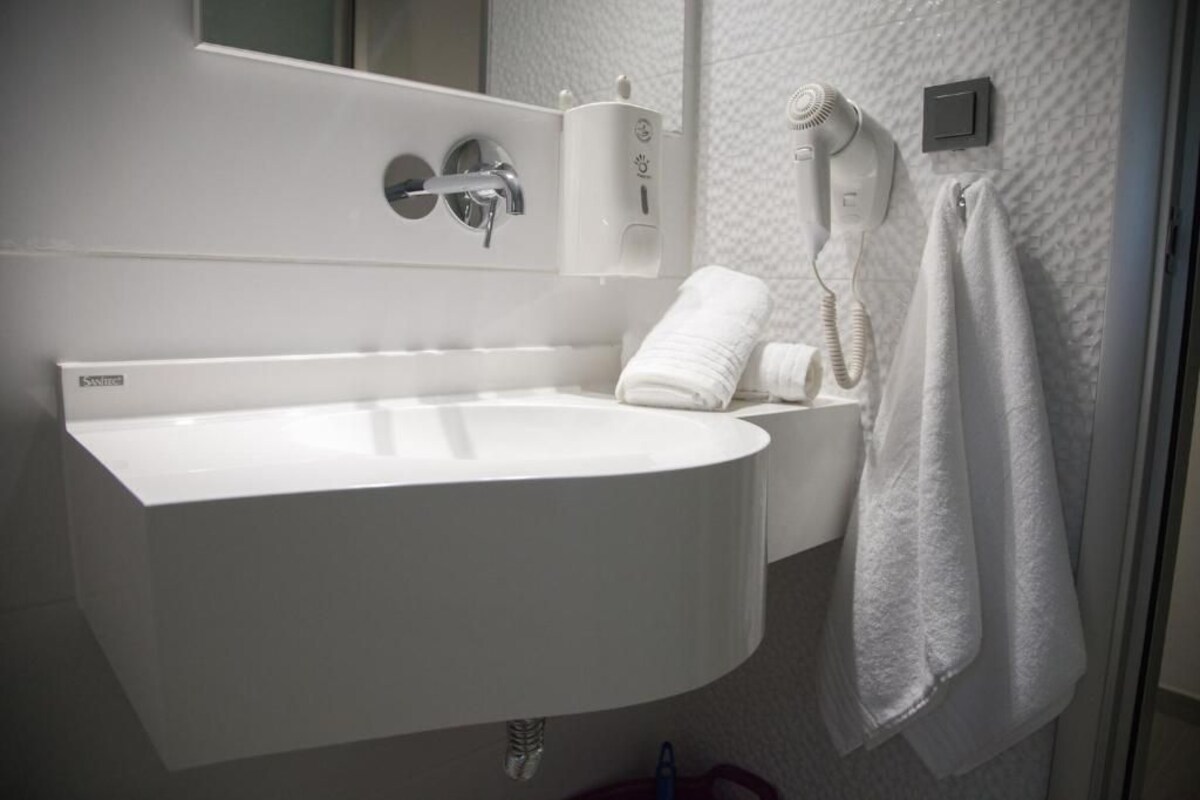 A modern bathroom with a white sink, a towel rack, and a hairdryer.