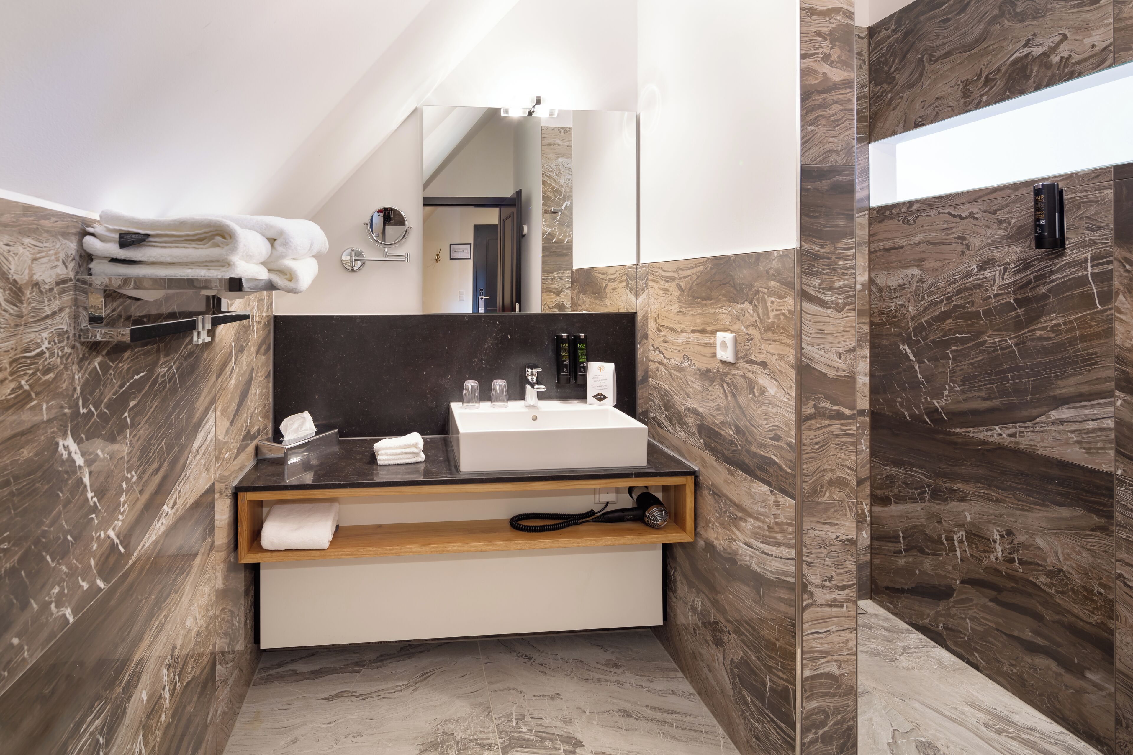 Un baño moderno con pared de mármol, un lavamanos blanco y un perchero.