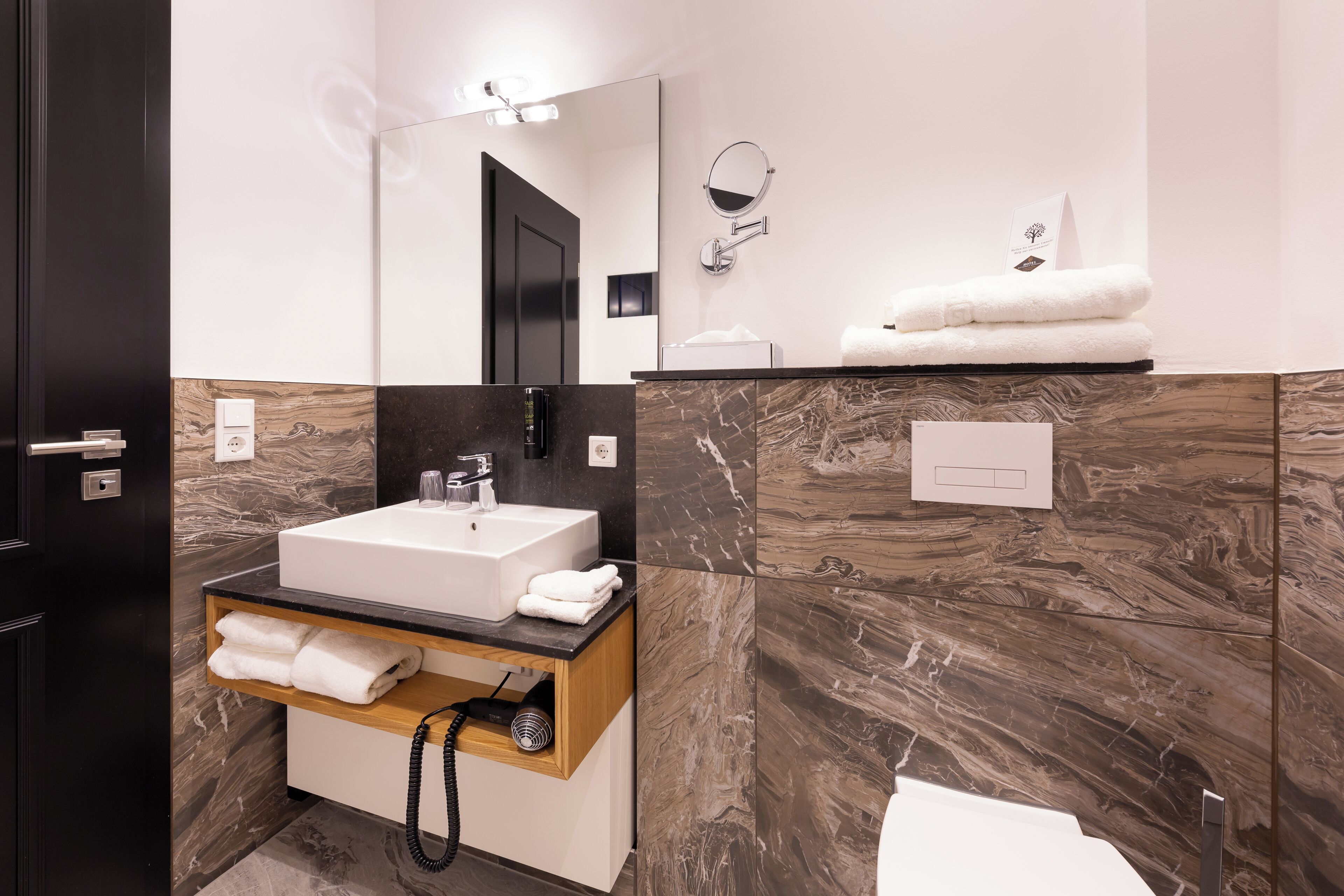 Un baño moderno con un espejo grande, un lavabo y un perchero para toallas.