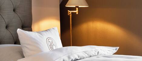 A neatly made bed with white linens and a tufted headboard.