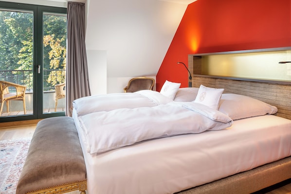 A hotel room with a large bed, a chair, and a view of the outdoors. - HRO Hotel Rittergut Osthoff GmbH (Georgsmarienhuette)