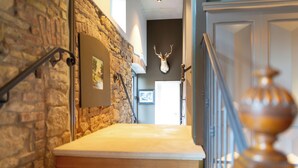 A staircase with a stone wall on one side and a wooden balustrade on the other. A mounted deer head is visible on the wall above the stairs. - HRO Hotel Rittergut Osthoff GmbH (Georgsmarienhuette)