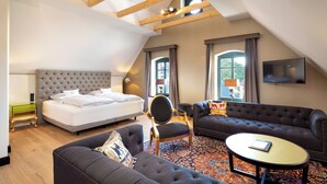 A modern hotel room with a large bed, two sofas, a small table, and a TV. - HRO Hotel Rittergut Osthoff GmbH (Georgsmarienhuette)