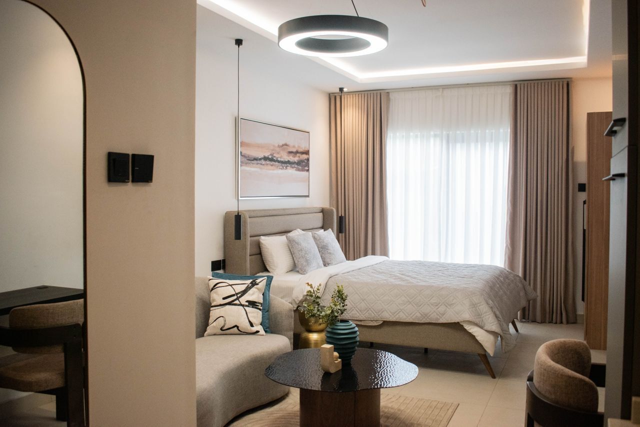 A modern hotel room with a large bed, a sofa, a coffee table, and a painting on the wall.