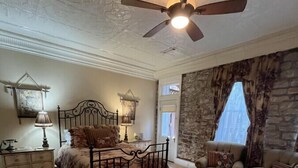 Quarto com cama, cadeira, penteadeira e ventilador de teto.