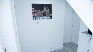 A room with a white wall, a framed picture of a cityscape, and a grey wooden floor. - South Harrow (Harrow)