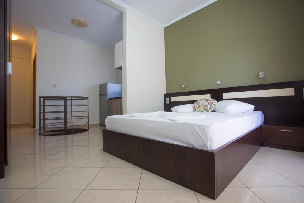 A hotel room with a large bed, a small table, a wardrobe, and a TV.