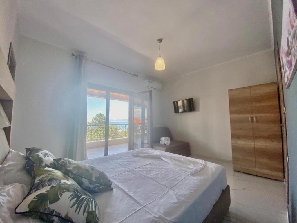 A bedroom with a bed, a wardrobe, a TV, and a balcony with a view.