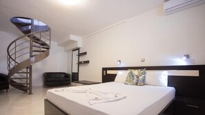 A modern hotel room with a spiral staircase, a large bed with white linens, a black headboard, and a small bedside table. - Villa Amalia Sun Beach (Volvi)